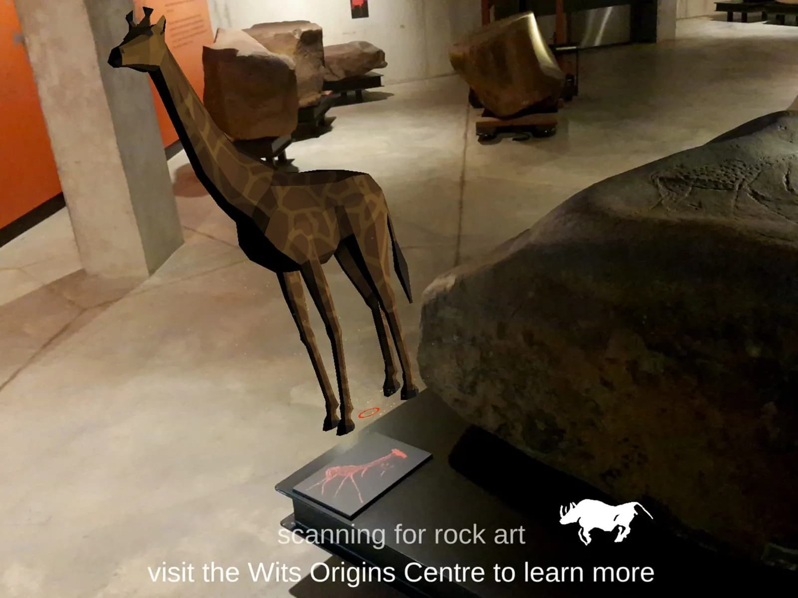 A low-poly giraffe stands beside an engraved rock in the Origins Centre, with the line scanning for rock art.
