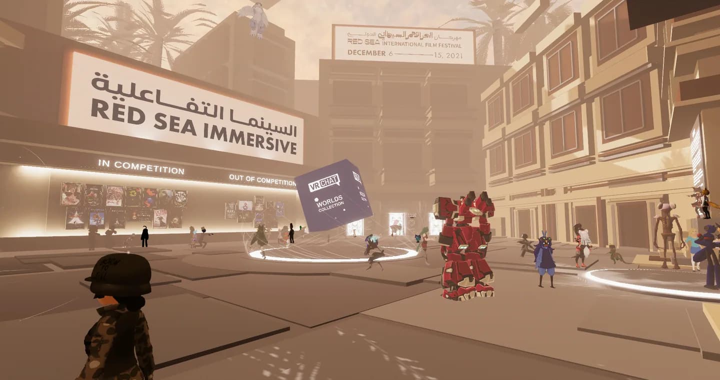 The Red Sea Immersive plaza in VRChat. Avatars mill around a floating "VRChat Worlds Collection" cube, in front of poster walls marked In Competition and Out of Competition, under a festival billboard for 6 to 15 December 2021.
