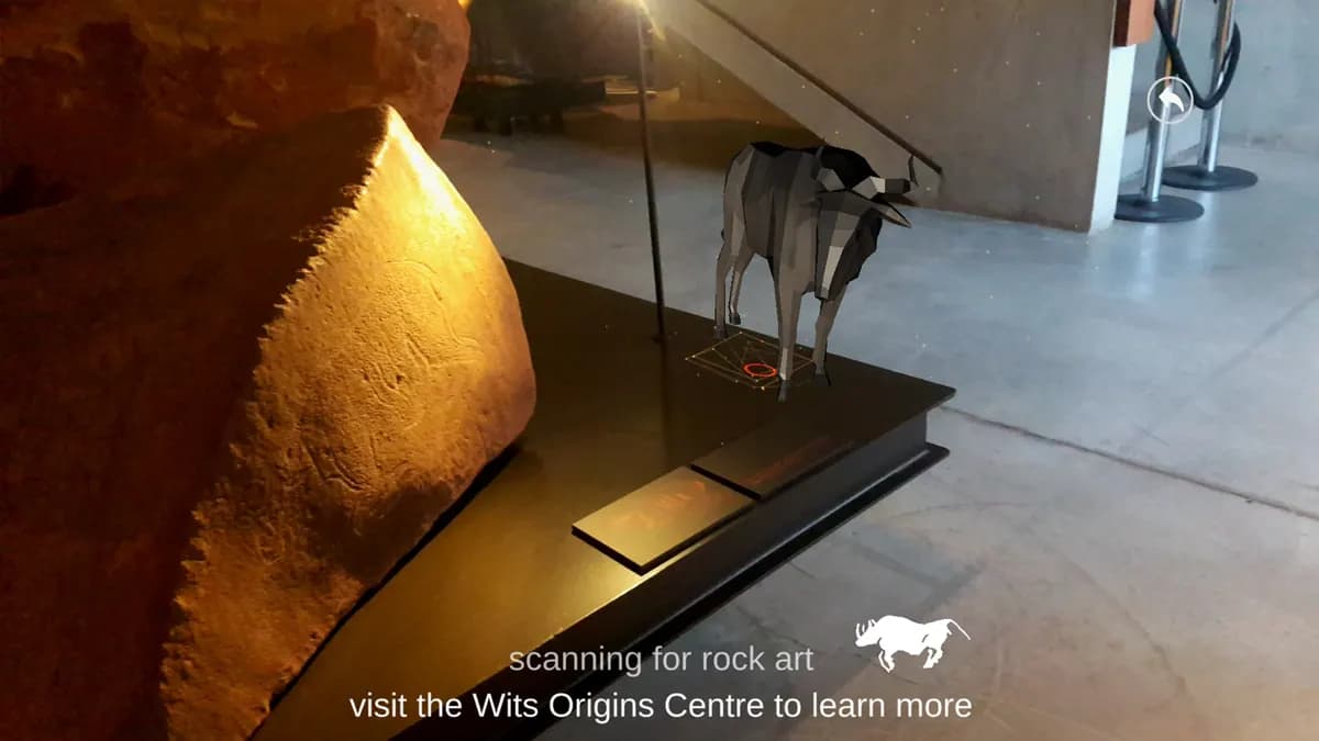 A low-poly antelope stands on a plinth beside an engraved rock while the app reads scanning for rock art.